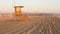 Iconic retro wooden orange lifeguard watch tower on sandy california pacific ocean beach illuminated by sunset rays