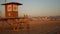 Iconic retro wooden orange lifeguard watch tower on sandy california pacific ocean beach illuminated by sunset rays