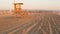 Iconic retro wooden orange lifeguard watch tower on sandy california pacific ocean beach illuminated by sunset rays. Private