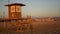 Iconic retro wooden orange lifeguard watch tower on sandy california pacific ocean beach illuminated by sunset rays. Private