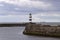 Iconic striped Seaham lighthouse on pier with clouds and sea walls