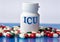 ICU - medical acronym on a white jar against the background of randomly scattered tablets