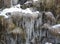 Icy crystals forming on forest water stream, winter landscape detail