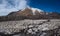 Icy glaciers on the slopes of Tolbachik Volcano viewed over a field with snow covered with sand and ash