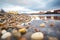 icy pebbles on a shore with cloud reflections