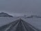 Icy ring road near JÃ¶kulsÃ¡rlÃ³n in southern Iceland with diminishing perspective and the rugged, snow-covered mountains.