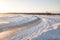 An icy road on a frozen lake around which lies a lot of snow at sunset on a winter day. Snow race and drift season on cars