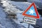 An icy road in winter with a sign Attention slippery