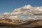 Idaho foot hills Ranch after a light snow under blue sky and broken clouds.