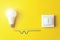 Idea, innovation, creativity concept with glowing light bulb and switch with wires phase, zero on Yellow Background. Power energy