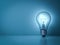 Idea light bulb glowing on the dark blue background with reflection