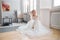 Ideal bride sitting on the floor, portrait of a girl in a long white dress. Beautiful hair and clean, soft skin. Wedding hairstyle