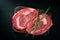 Ideal raw rib eye beef steak with rosemary on black wooden background