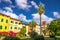 Idee In Circolo park with palms, colorful buildings and bell tower on Piazza Dante Alighieri square in historical centre of Pisa