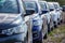 Identical blue cars stand in a row in a Parking lot or market for sale. View of the side mirrors, the Dealership. New car sales.