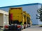 Idle trucks lined up along tall industrial storage building