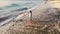 Idyllic aerial drone view of young thoughtful woman standing on beach watching scenic view of seascape during amazing