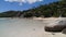 Idyllic beach with big limestones, hill with Tropical forest and some Holiday houses.