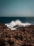 Idyllic beach scene featuring large rolling waves crashing against rocky shoreline