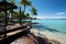 Idyllic beachfront view, wooden platform, palm trees, crystal-clear waters, blue skies