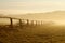 Idyllic fence on a misty field at sunrise