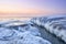 Idyllic frozen rocky shore with pink sky on the horizon, perfect for wallpapers