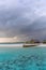 An idyllic island in Maldive in a stormy weather afternoon. Super clear water, white sand, traditional huts and tropical climate f
