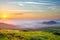 Idyllic landscape with green grass covered morning mountains with distant peaks and wide valley full of thick white cloudy fog