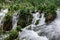 Idyllic landscape of a lush waterfall cascading down a rocky cliff surrounded by lush vegetation