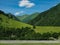 Idyllic mountain landscape. In the distance grazing herd of cows. Alpine meadow