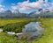 Idyllic mountain landscape in the summertime with a creek and small pond in the foreground