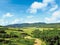 Idyllic panoramic view of tropical countryside with green hills with lush vegetation under tropical blue sky with white clouds.