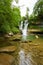 Idyllic rain forest waterfall, stream flowing in the lush green forest.