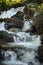 Idyllic scene of nature featuring a tranquil waterfall cascading over a cluster of large grey stones