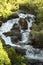 Idyllic scene of nature featuring a tranquil waterfall cascading over a cluster of large grey stones