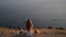 idyllic scenery of beautiful young woman sitting and dreaming on sea shore with two small chihuahua dogs with sailing