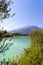 Idyllic shore landscape with pebble beach, blue water, flowers and mountains