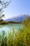 Idyllic shore landscape with pebble beach, blue water, flowers and mountains