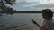 Idyllic shot of a lady on her phone with a lake in the background.