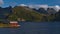 Idyllic view of small shed with red facade located on the shore of fjord Selfjorden with the mountains of FlakstadÃ¸ya.