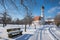 Idyllic village church, wintry road and wooden bench