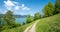 Idyllic walkway at Leeberg hill, view to lake Tegernsee, blue sky with clouds. spring landscape
