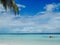 Idyllic white beach with palm trees and people kayaking