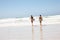 If in doubt, paddle out. Rearview shot of young surfers running into the waves with their surfboards.