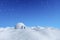 Igloo icehouse under blue sky with snowfall.