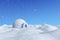 Igloo icehouse under blue sky under snowfall.
