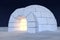 Igloo icehouse with warm light inside under night sky with stars