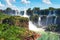 Iguazu waterfalls in Argentina, view from Devil`s Mouth. Panoramic view of many majestic powerful water cascades creating mist