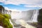 Iguazu waterfalls in Argentina, view from Devil`s Mouth. Panoramic view of many majestic powerful water cascades with mist and lo