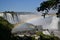 Iguazu waterfalls rainbow on sunny, blue sky and bridge